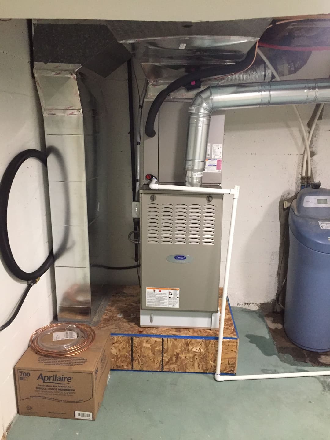 Furnace and humidifier setup in a basement, with ductwork and water tank visible.