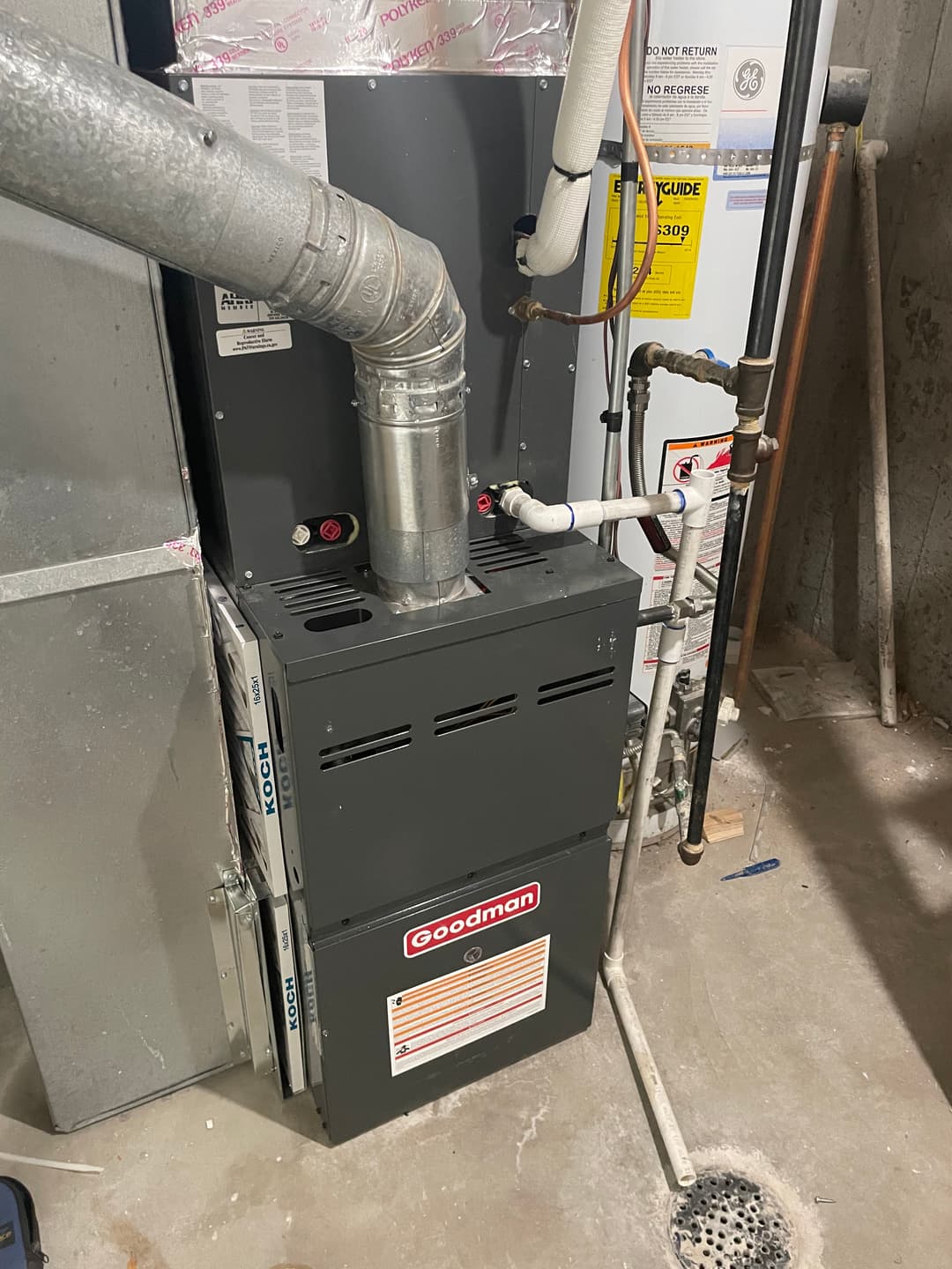 Goodman furnace with ventilation pipe in a basement setting, showcasing heating system components.