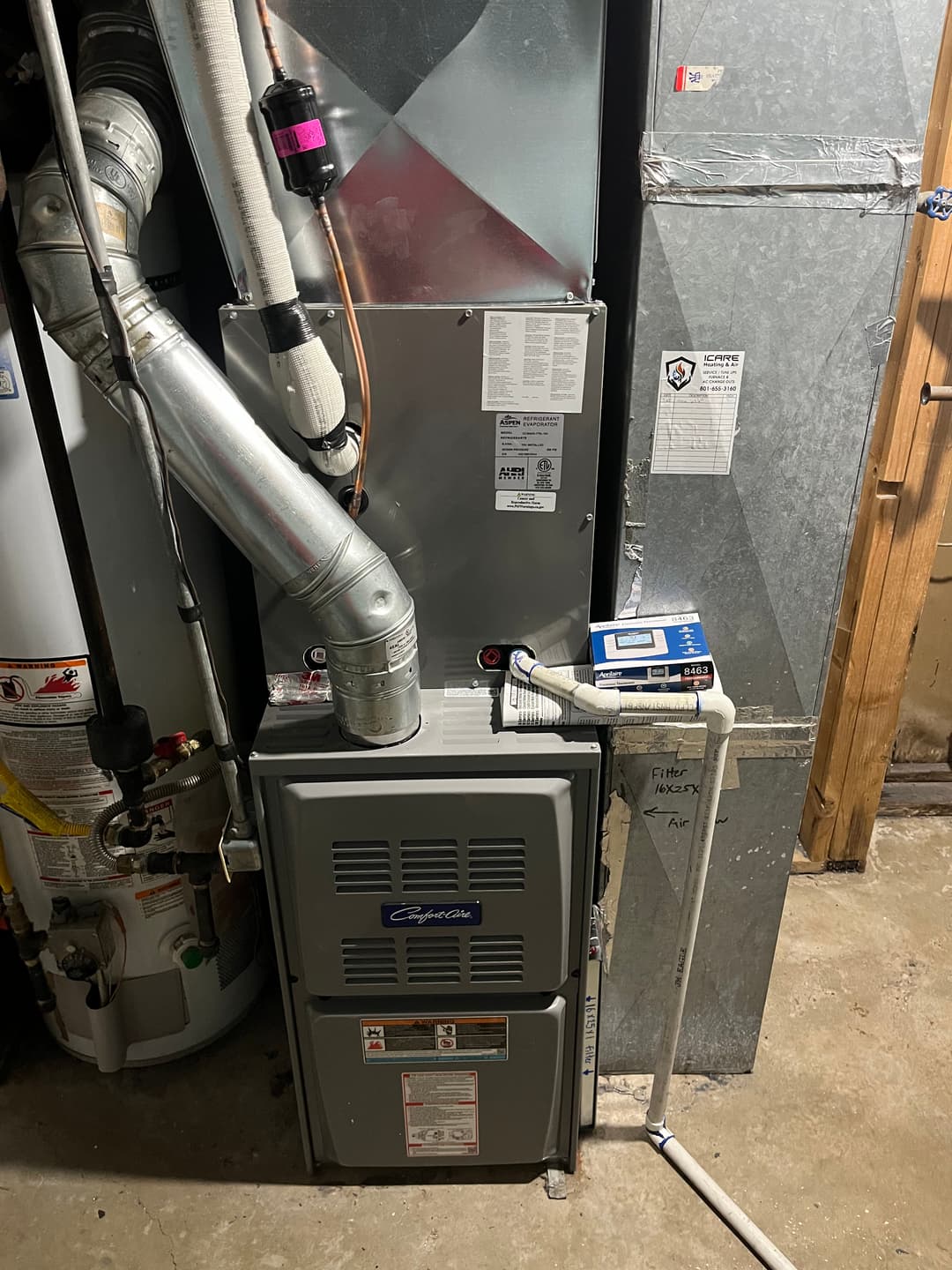 Furnace installed in a basement, with ductwork and nearby water heater visible.