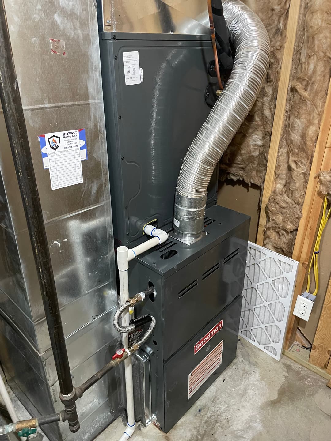 Gas furnace installation with vent pipe and ductwork in a basement setting.