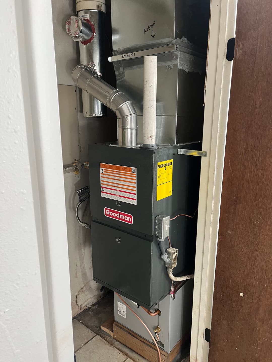 Goodman furnace installation in a utility room with ventilation and pipes.